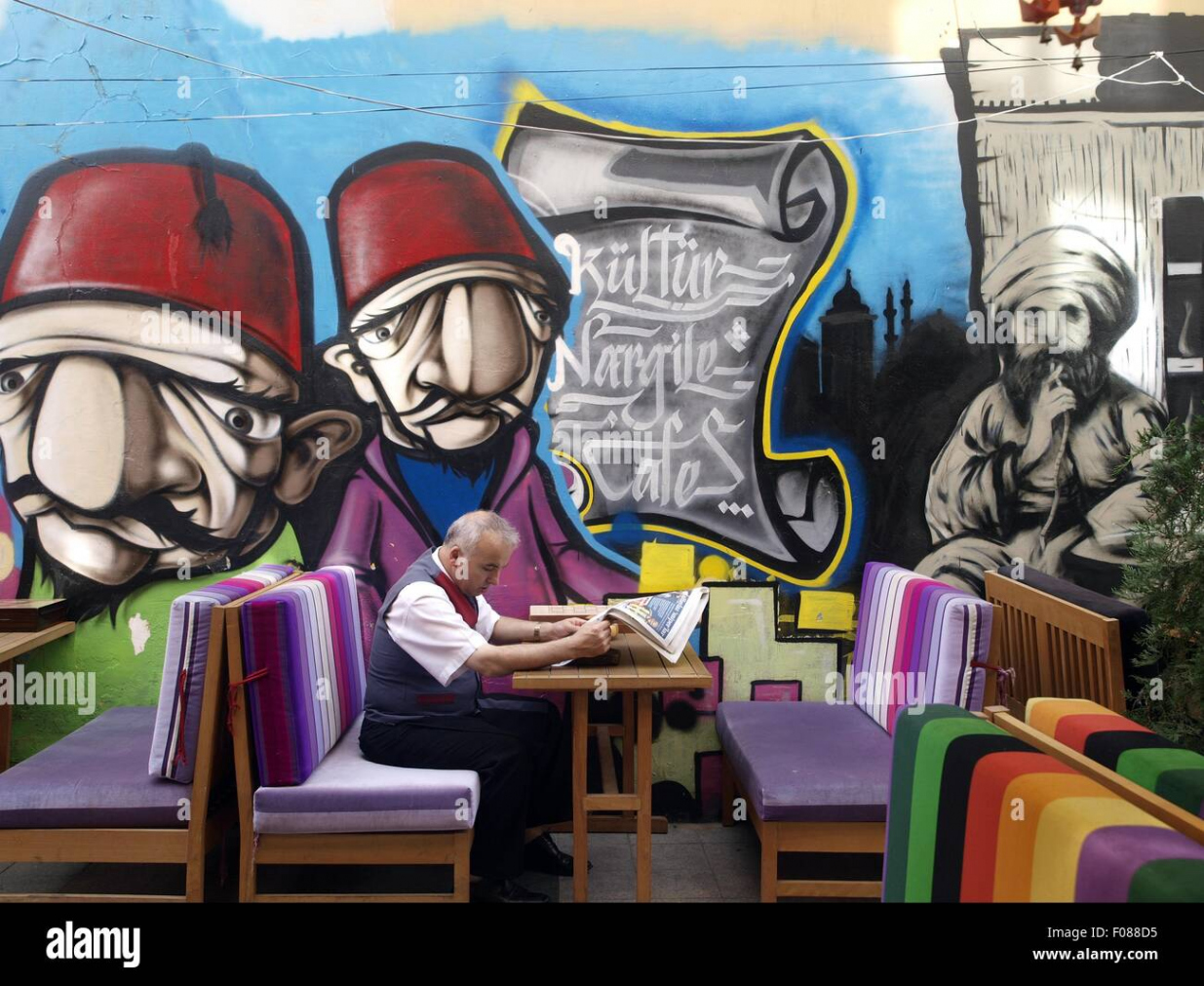 People sitting beside graffiti wall at street cafe and reading