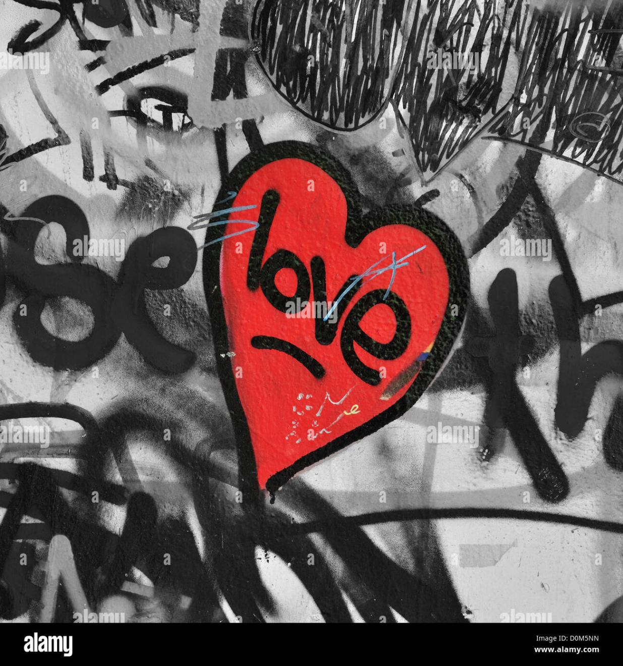 Red painted love heart on graffiti covered black and white wall