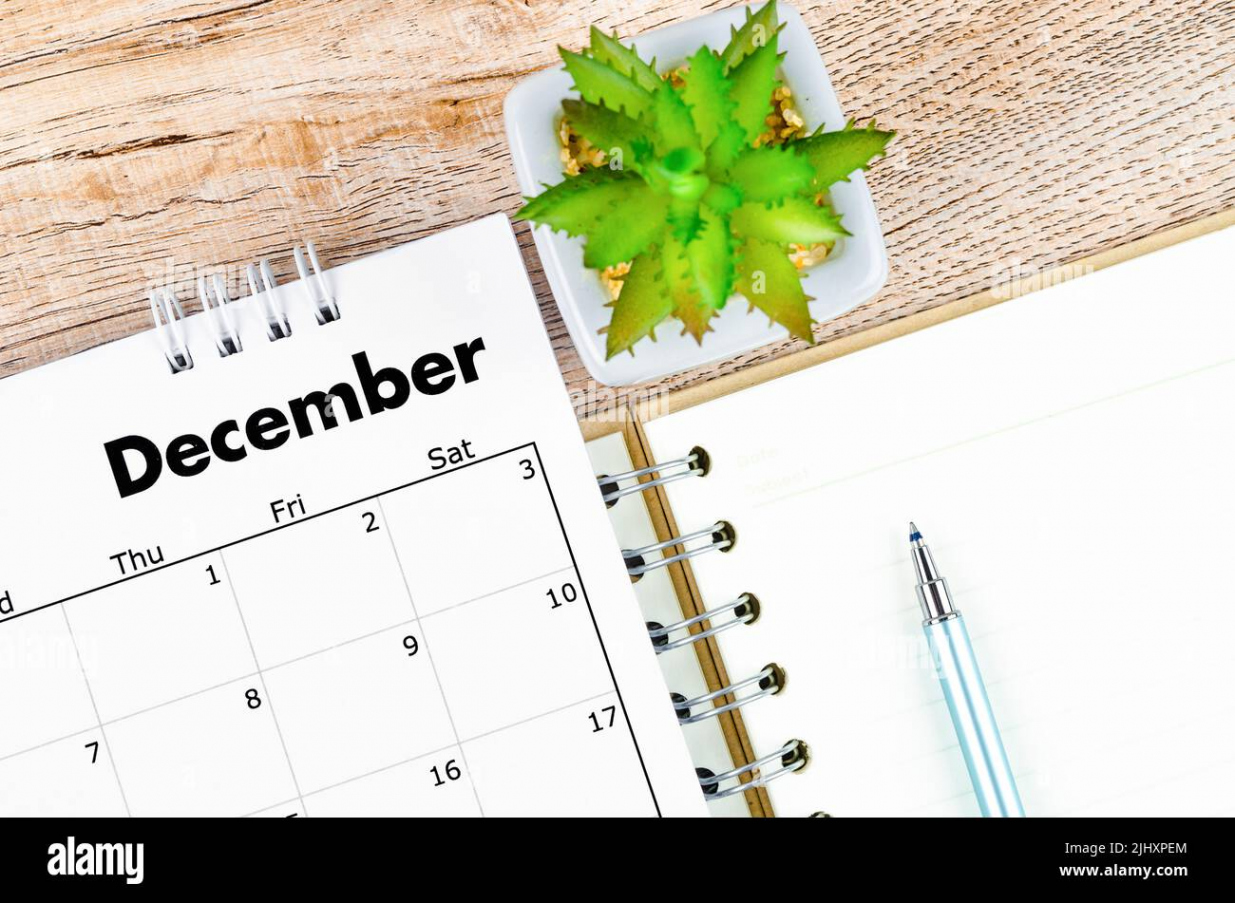 December  desk calendar and open diary with pen on wooden