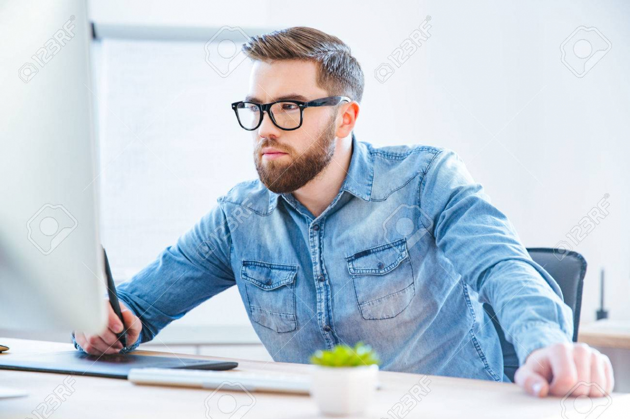 Serious Concentrated Young Man Designer Drawing With Graphic Pen